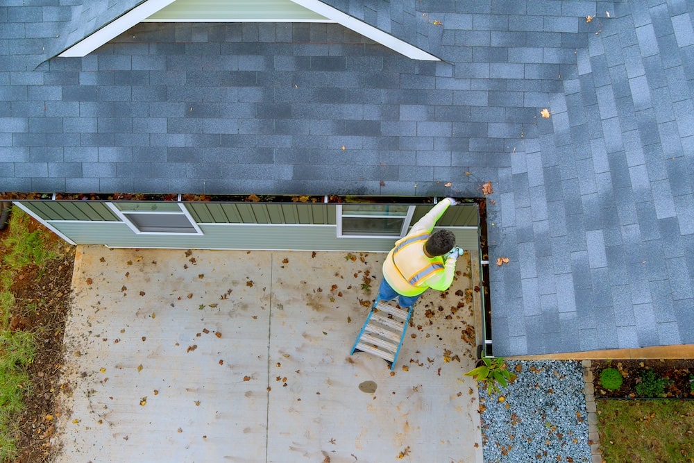 an-employee-is-cleaning-a-clogged-roof-gutter-drai-2023-11-27-05-04-16-utc-min